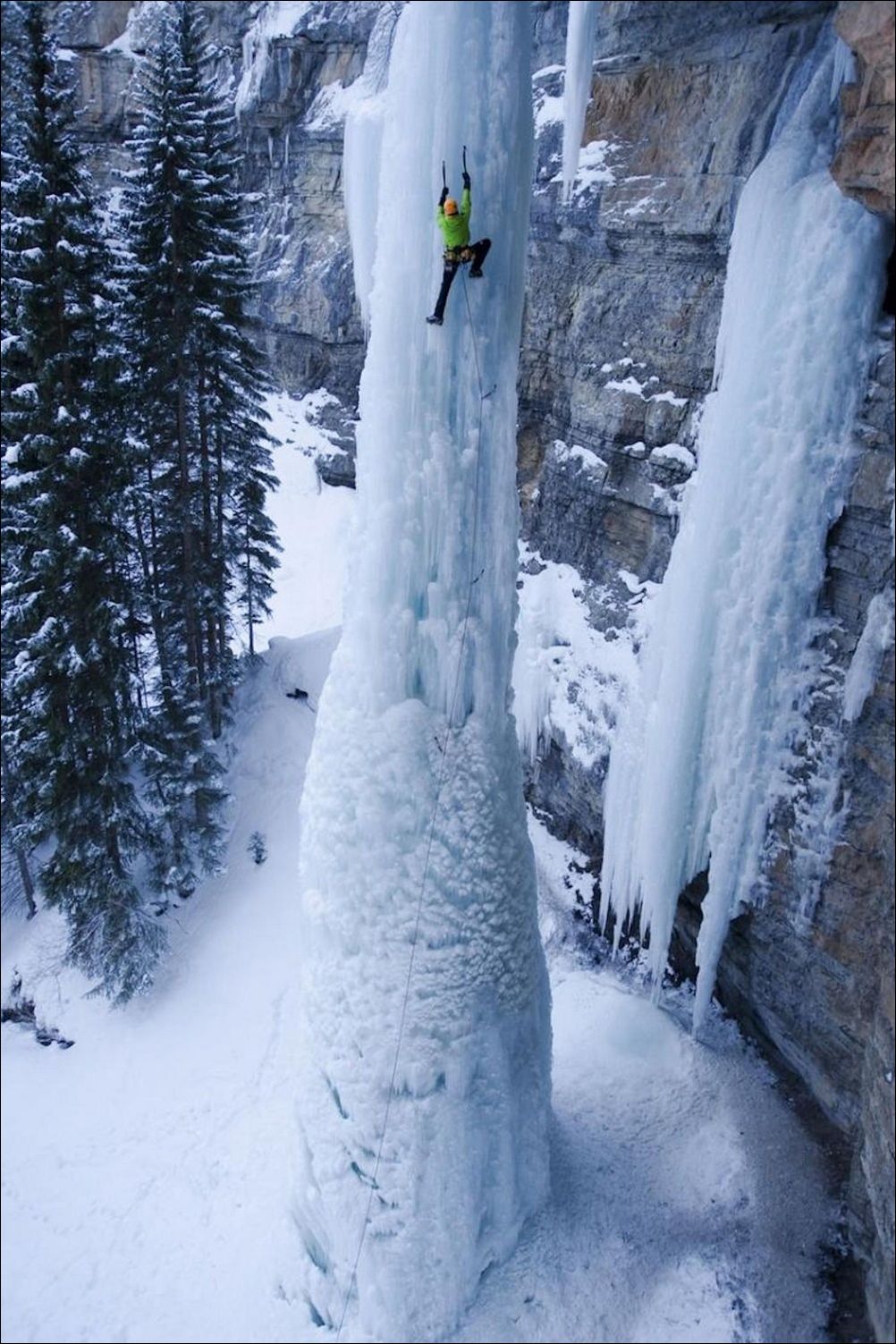 Альпинист взбирается по глыбе льда замёршего водопада